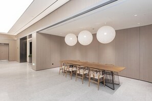 A modern conference room with a long wooden table and chairs, large spherical pendant lights, and a minimalist design.