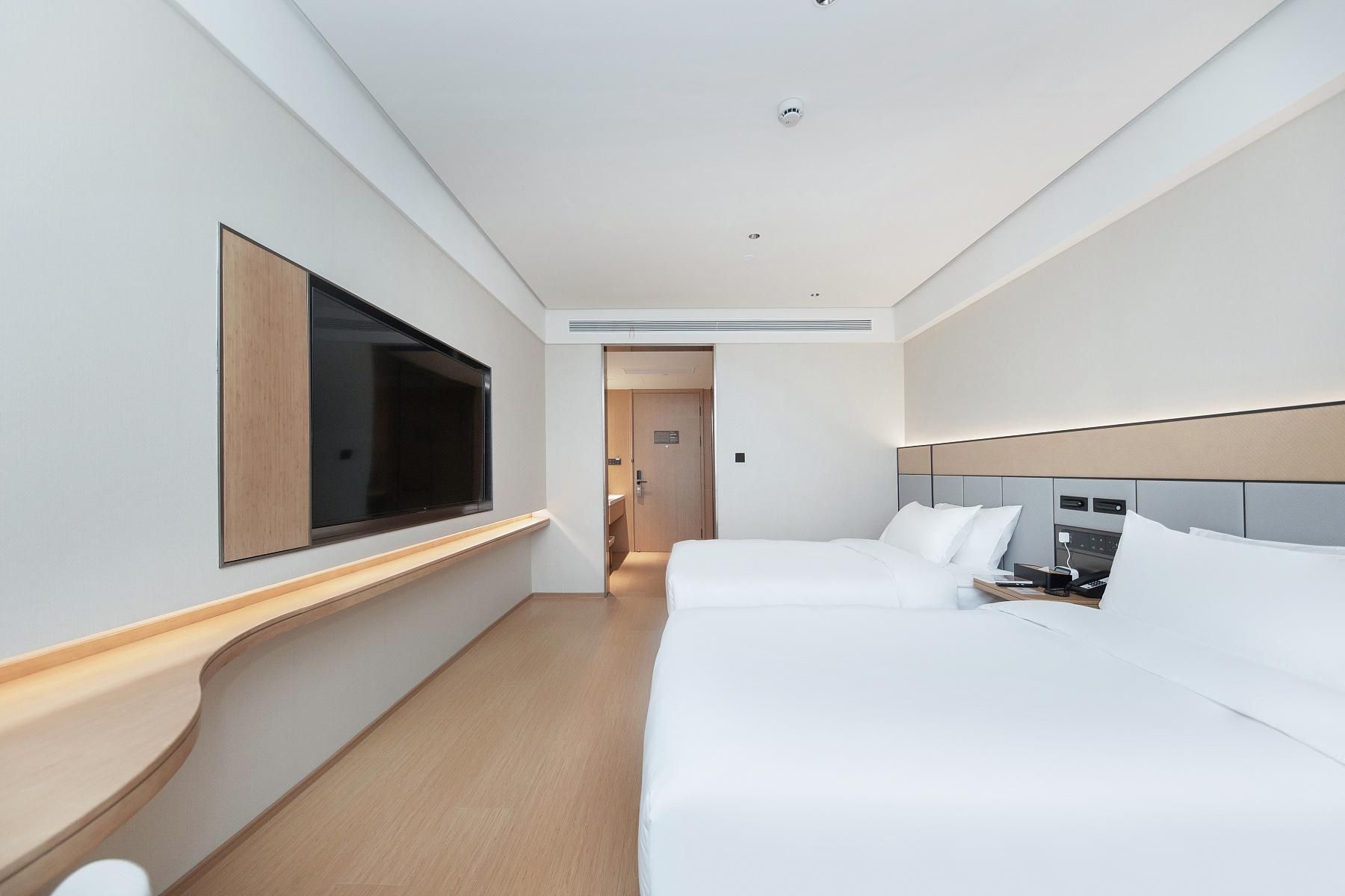 A hotel room with a large bed, a TV mounted on the wall, and a door leading to a bathroom.