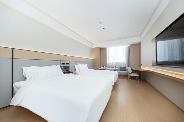 Habitación de hotel con dos camas, un escritorio, una silla y un ventanal grande.