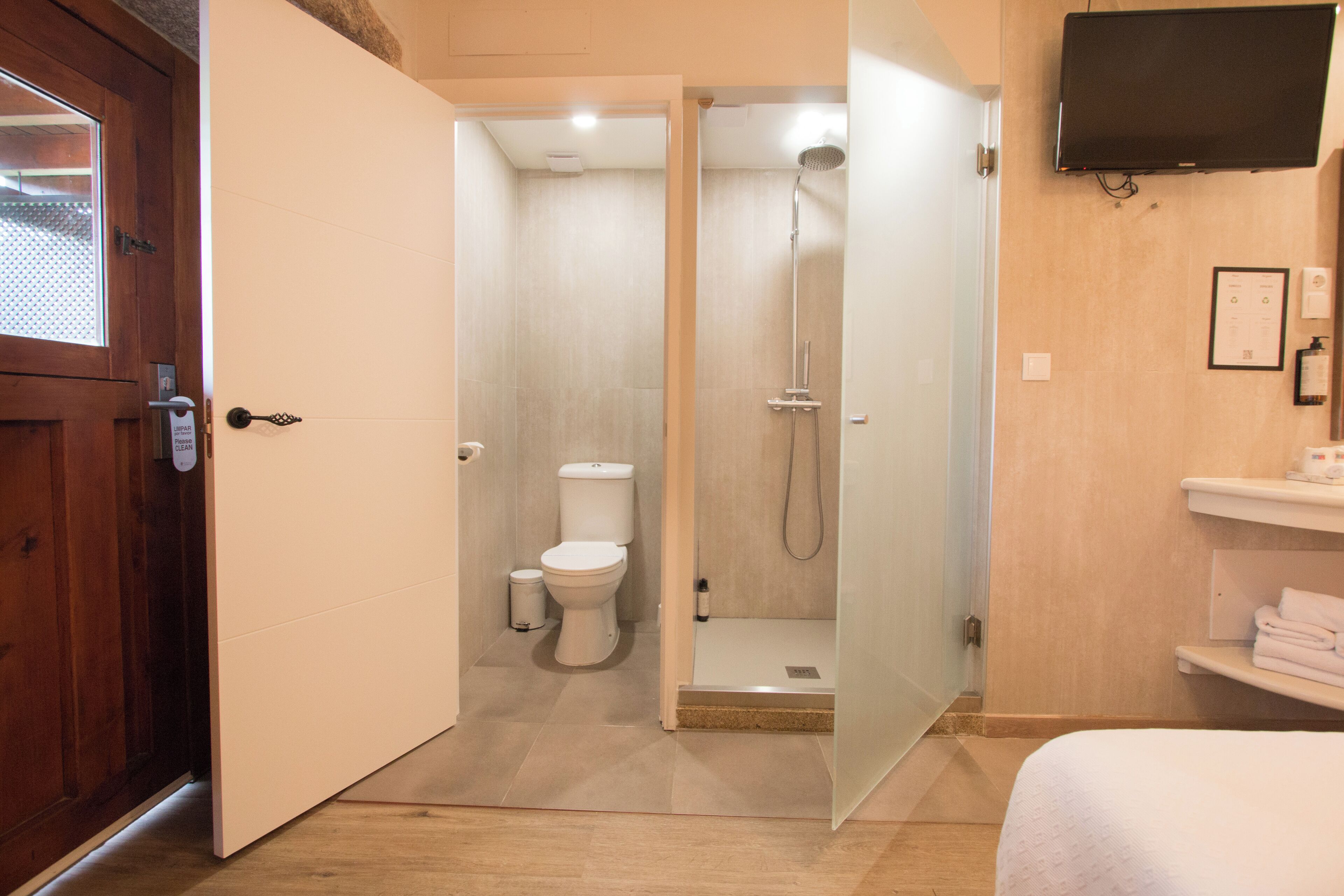 Une salle de bain moderne équipée d’une douche, de toilettes et d’un téléviseur fixé au mur.