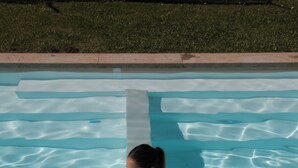 Una persona sentada en una piscina azul cristalina con ondulaciones visibles.