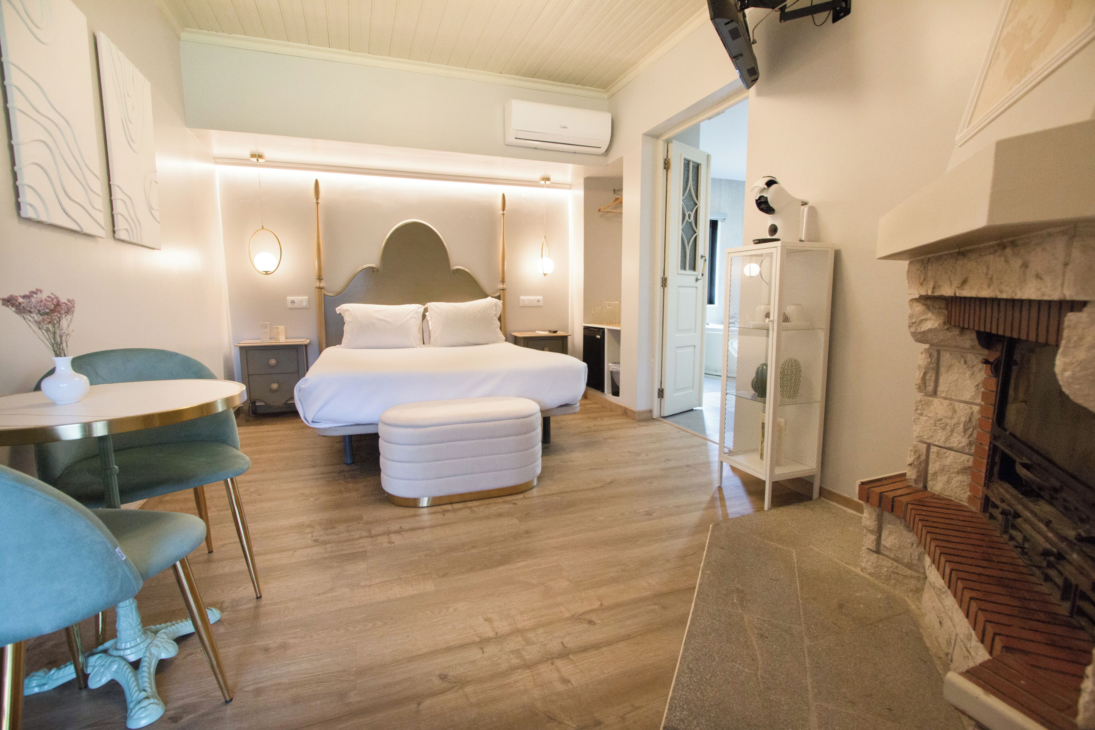 Un dormitorio moderno con una cama grande, mesitas de noche, una mesa redonda con sillas y una chimenea.
