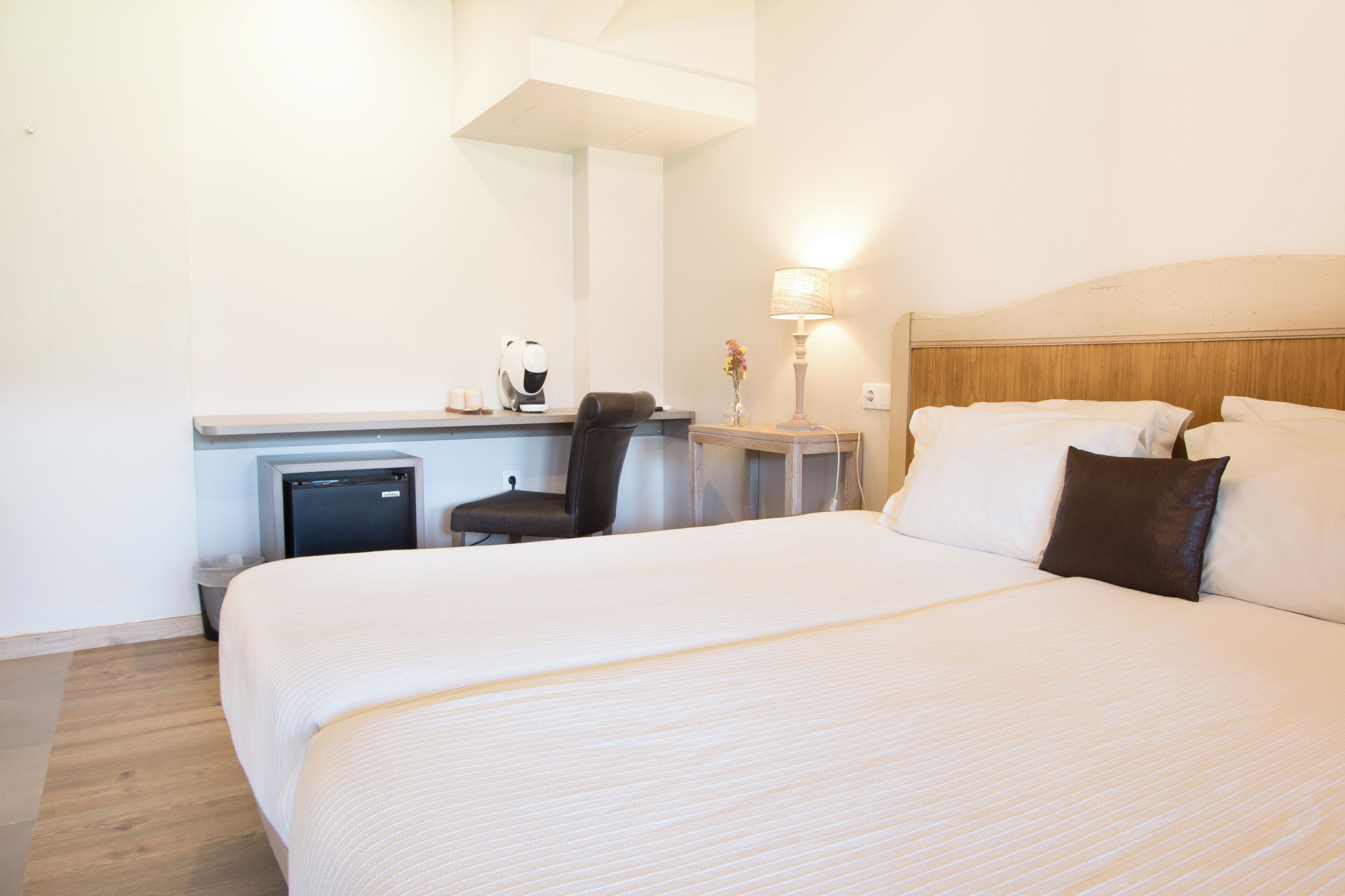 Una habitación de hotel con una cama grande, un escritorio con computadora, una silla y una lámpara.