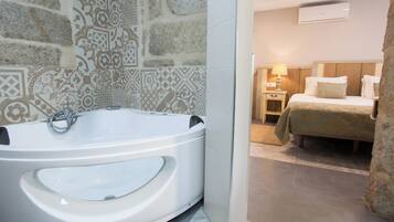 Een badkamer met een groot bad, een douche en een bed met een houten hoofdeinde.