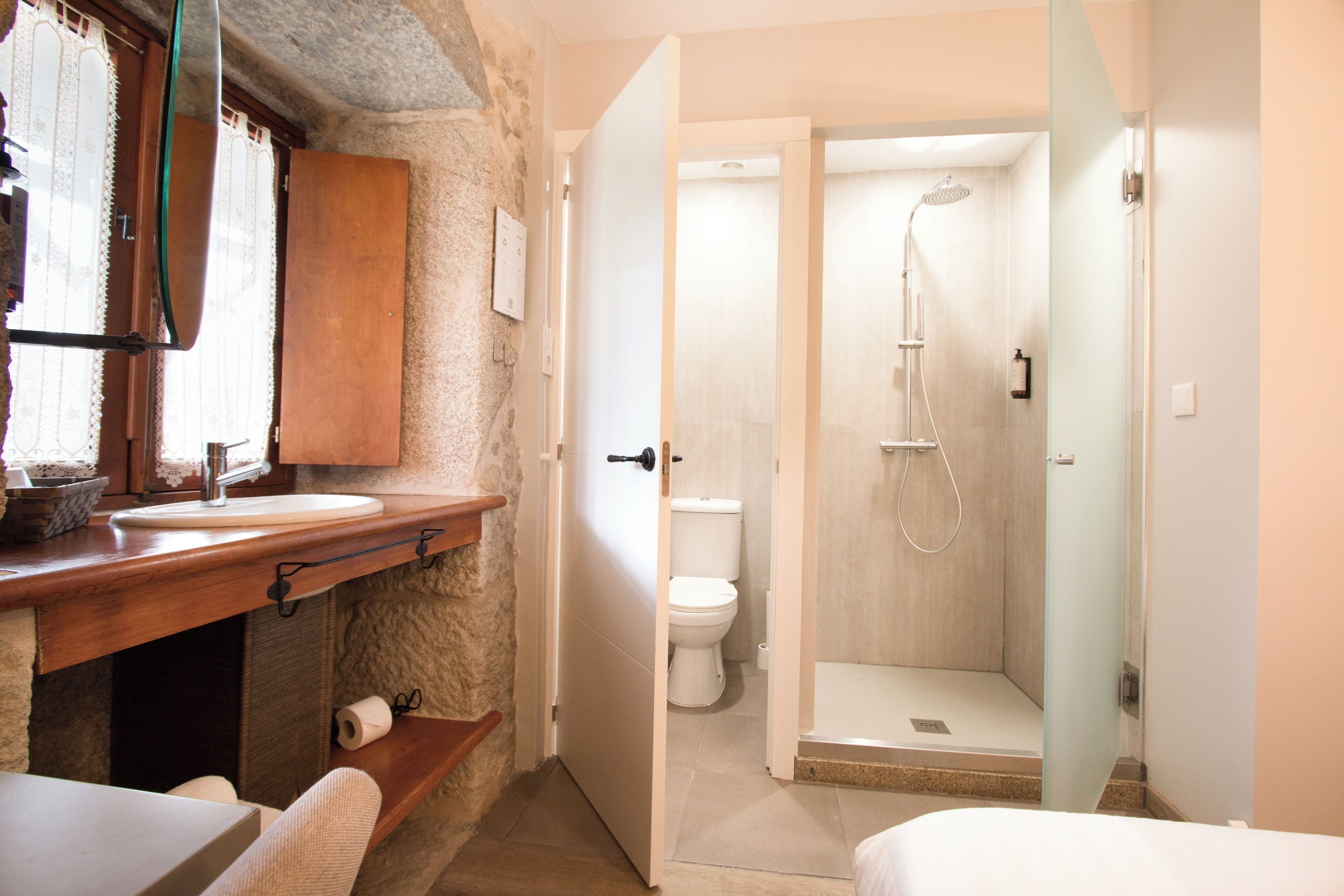 A bathroom with a wooden vanity, a toilet, and a shower area.