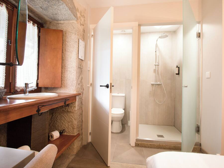 A bathroom with a wooden vanity, a toilet, and a shower area.