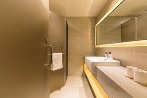 A modern bathroom with a glass shower enclosure, a vanity with a sink and mirror, and a towel rack. - Ji Hotel (Hangzhou)
