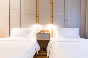 A hotel room with two beds, a nightstand, and a wall-mounted light fixture. - Ji Hotel (Hangzhou)