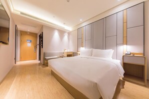 A modern hotel room with a large bed, bedside tables, a flat-screen TV, and a wooden floor. - Ji Hotel (Hangzhou)