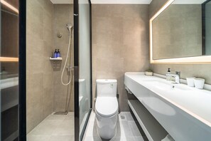 A modern bathroom with a glass-enclosed shower, a white toilet, and a large mirror above the sink.
