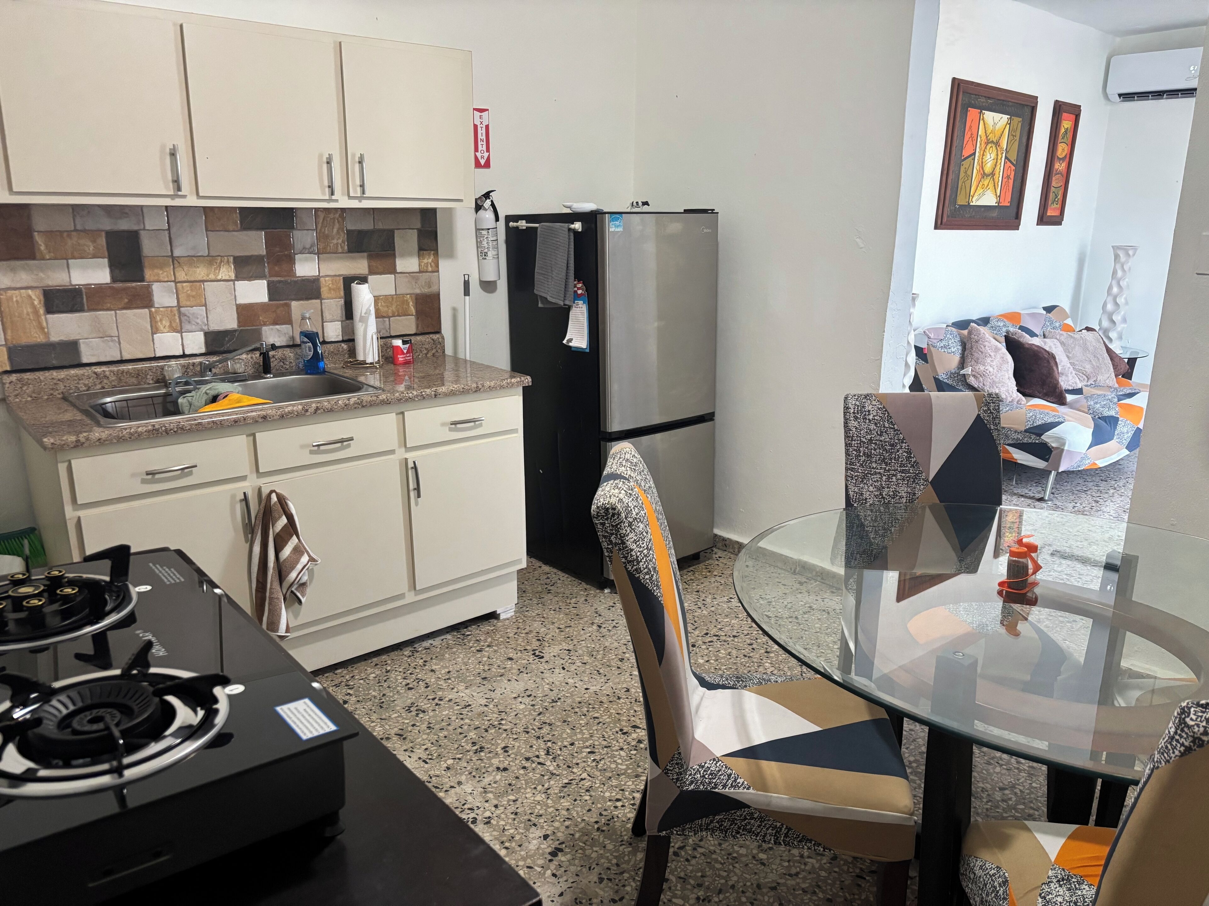 A compact kitchen with a gas stove, a refrigerator, and a tiled backsplash.