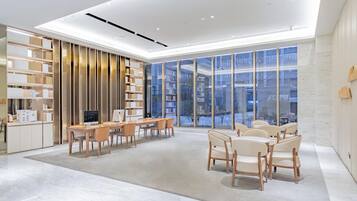 A modern interior with a dining area, bookshelves, and large windows.