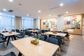 A modern conference room with tables and chairs, a large window, and a colorful mural on the wall. - Hanting Hotel (Suzhou)