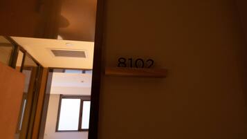 Een gang met een deur met het opschrift '8102' en een raam op de achtergrond.
