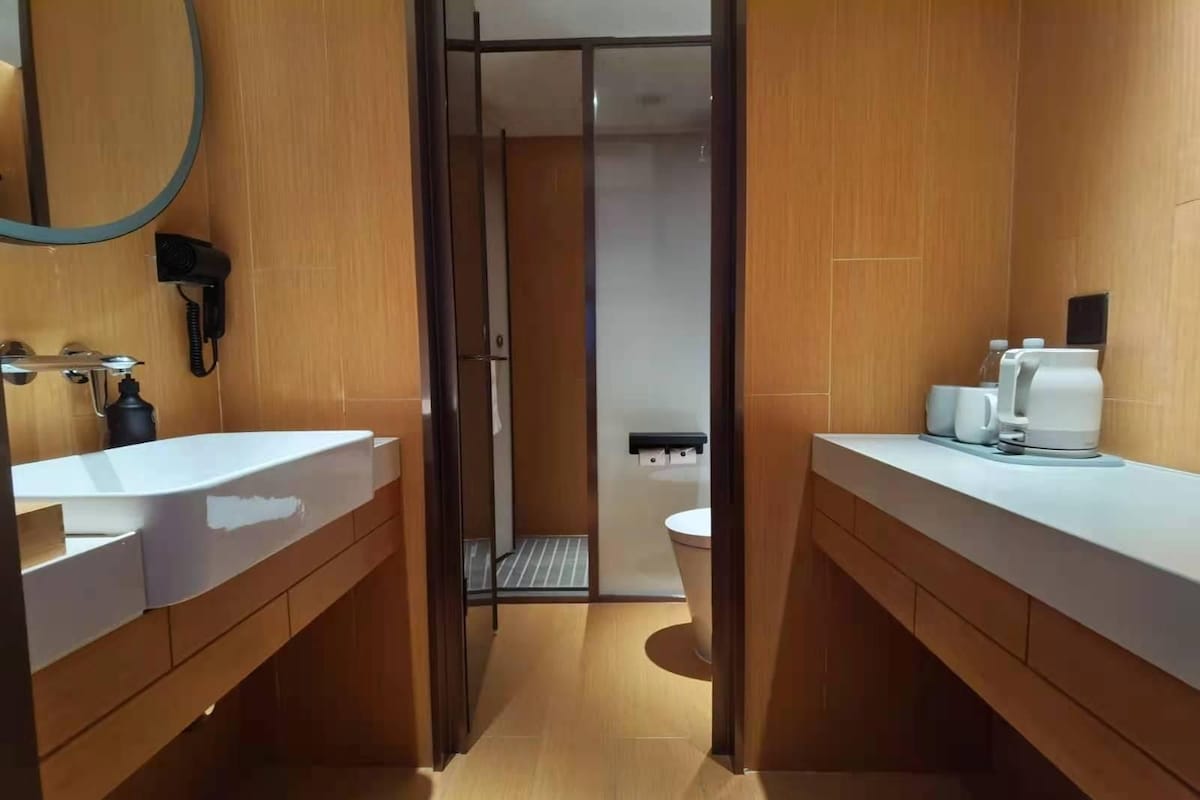 A modern bathroom with a wooden vanity, a sink, a mirror, and a shower area.