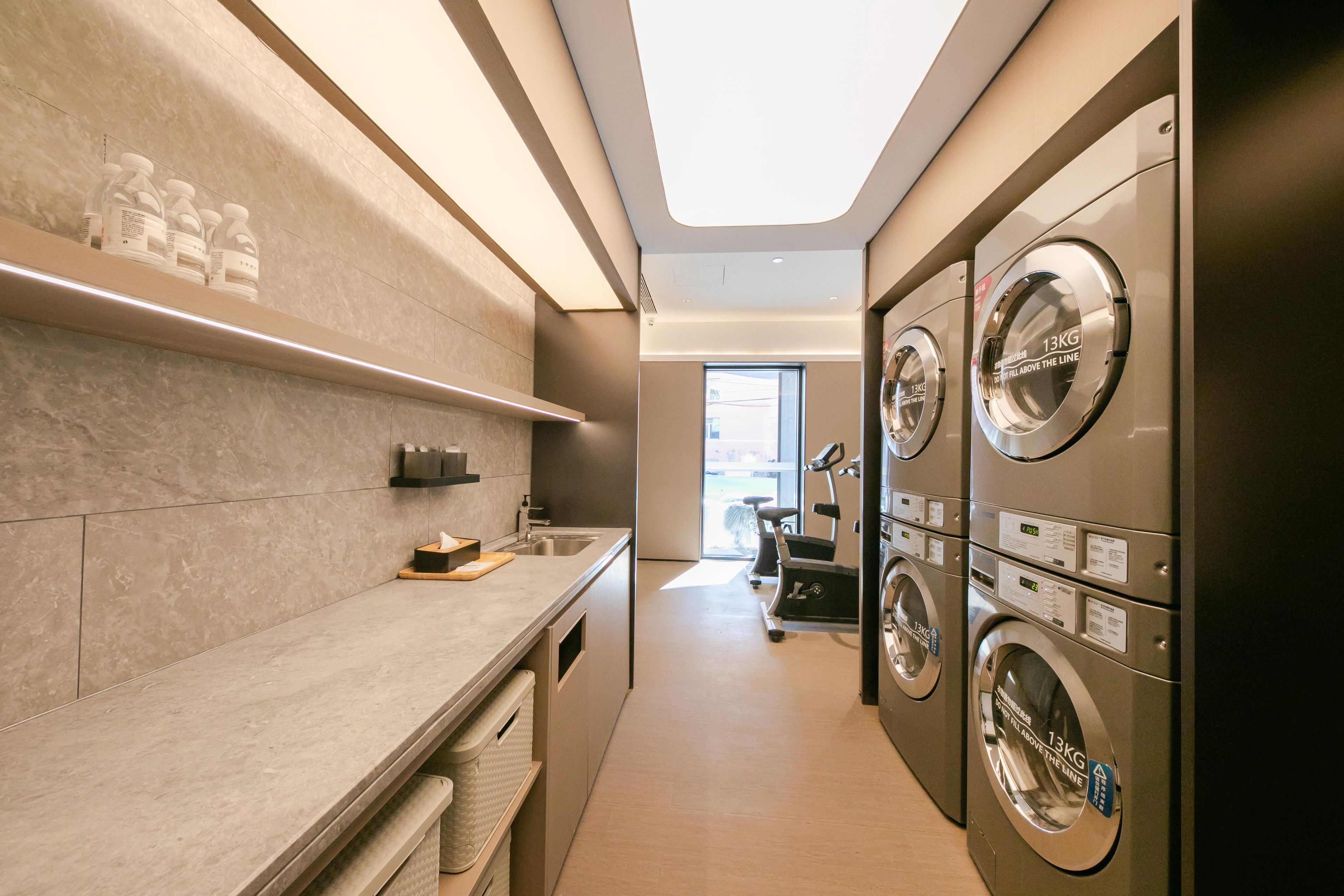 A laundry room with multiple washing machines, a sink, and a window providing natural light.