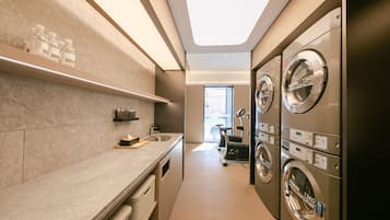 A laundry room with multiple washing machines, a sink, and a window providing natural light.