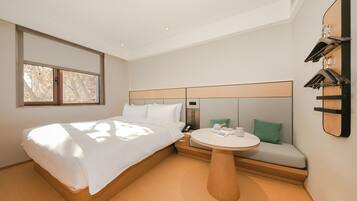 A hotel room with a bed, a round table, a sofa, and a wall-mounted clock.