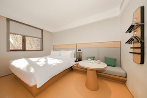 A hotel room with a bed, a round table, a sofa, and a wall-mounted clock. - Ji Hotel (Beijing)