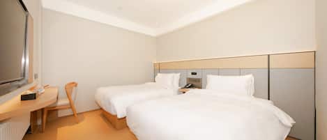 A hotel room with two beds, a desk, a chair, a television, and a wall-mounted control panel.