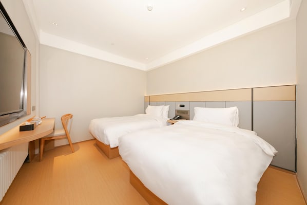 A hotel room with two beds, a desk, a chair, a television, and a wall-mounted control panel. - Ji Hotel (Beijing)