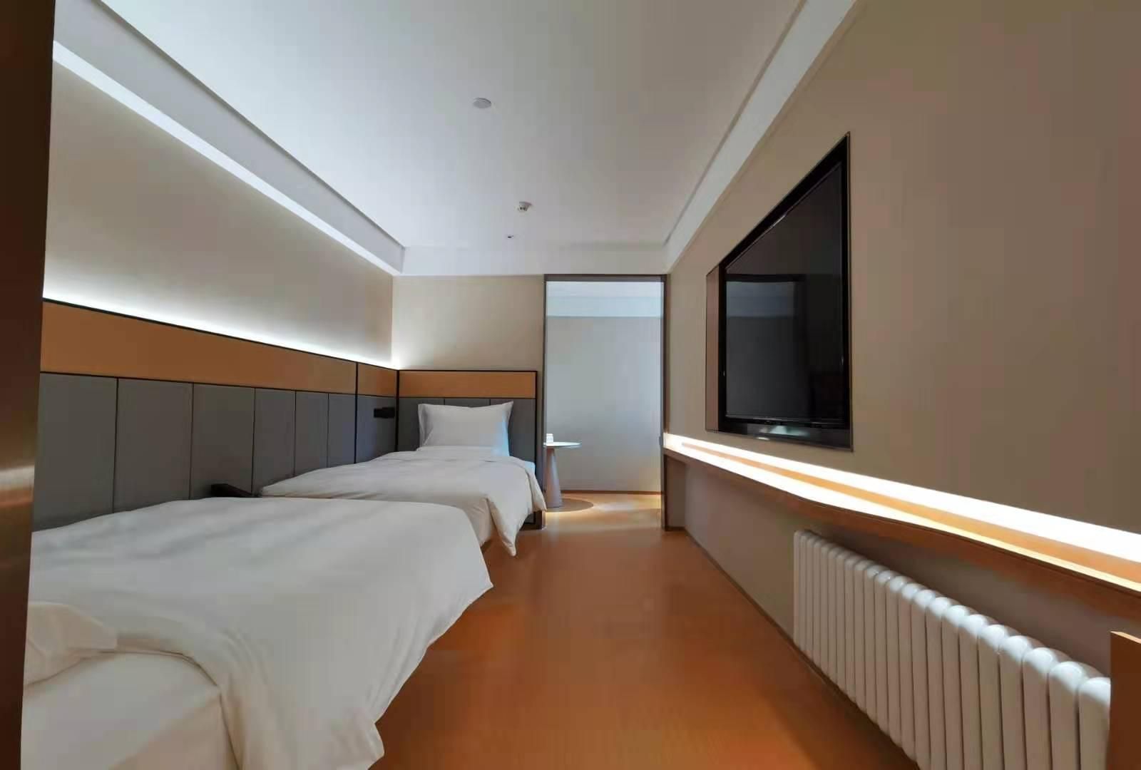 Habitación de hotel con dos camas, un ventanal amplio y un televisor.