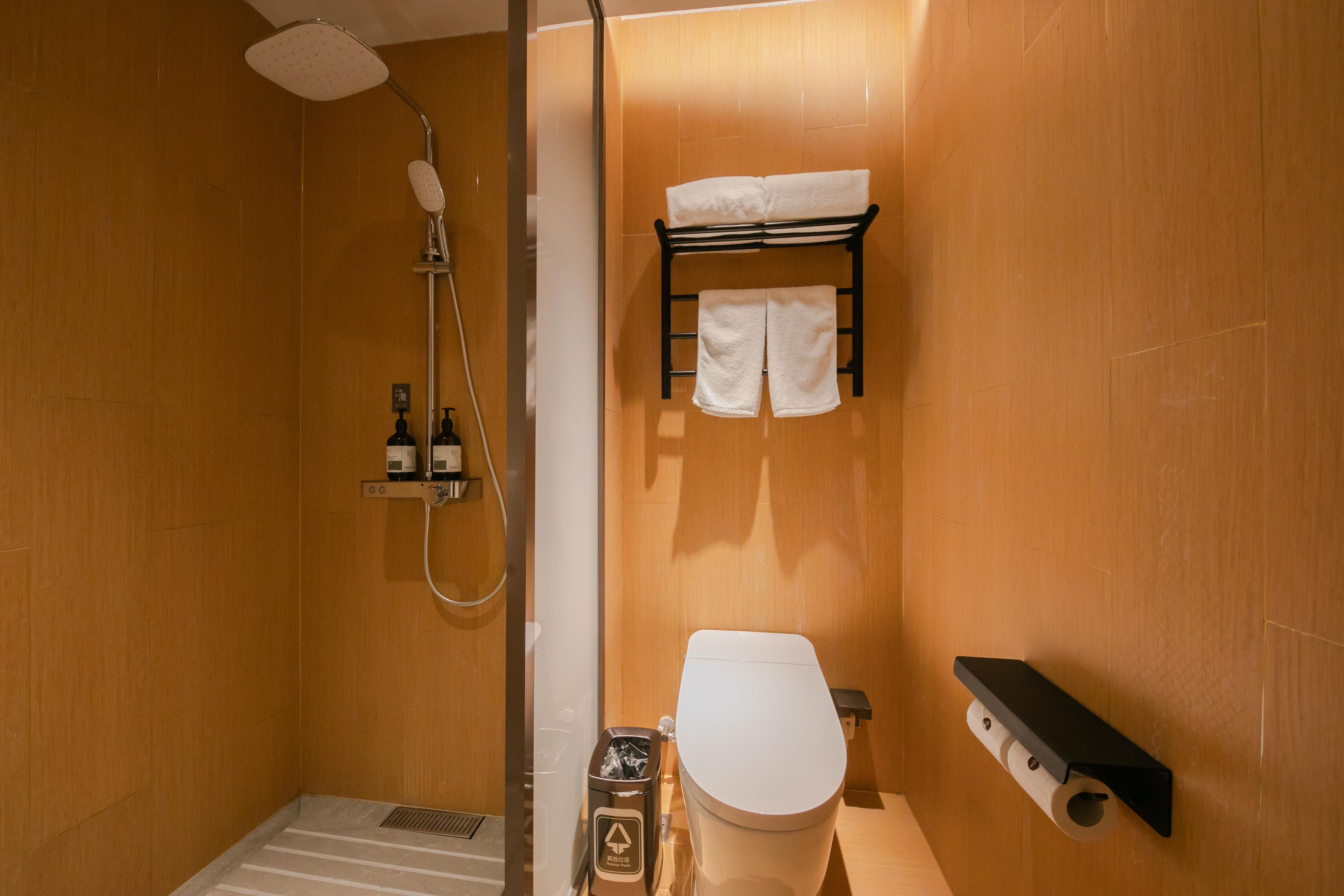 A compact bathroom with a shower, toilet, and towel rack.