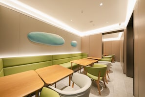 A modern interior with a row of tables and green seating. - Ji Hotel (Beijing)