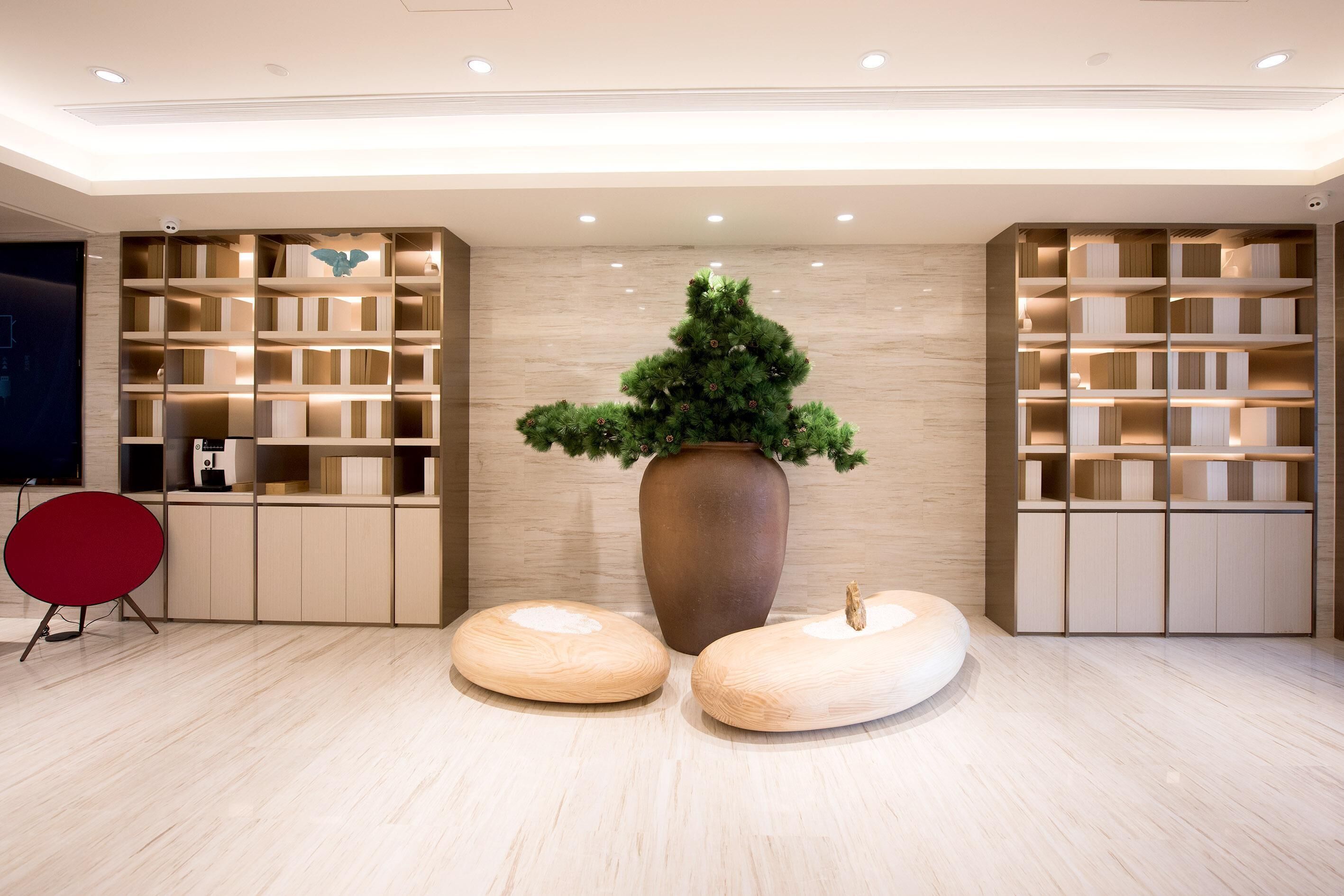 A modern interior with a large vase, two stools, and built-in shelving.