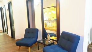 Un pasillo con dos sillones azules y una pequeña mesa con un florero.