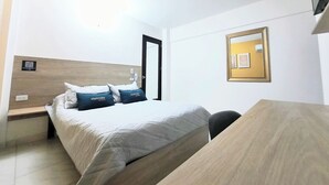Una habitación de hotel con cama, escritorio y espejo.