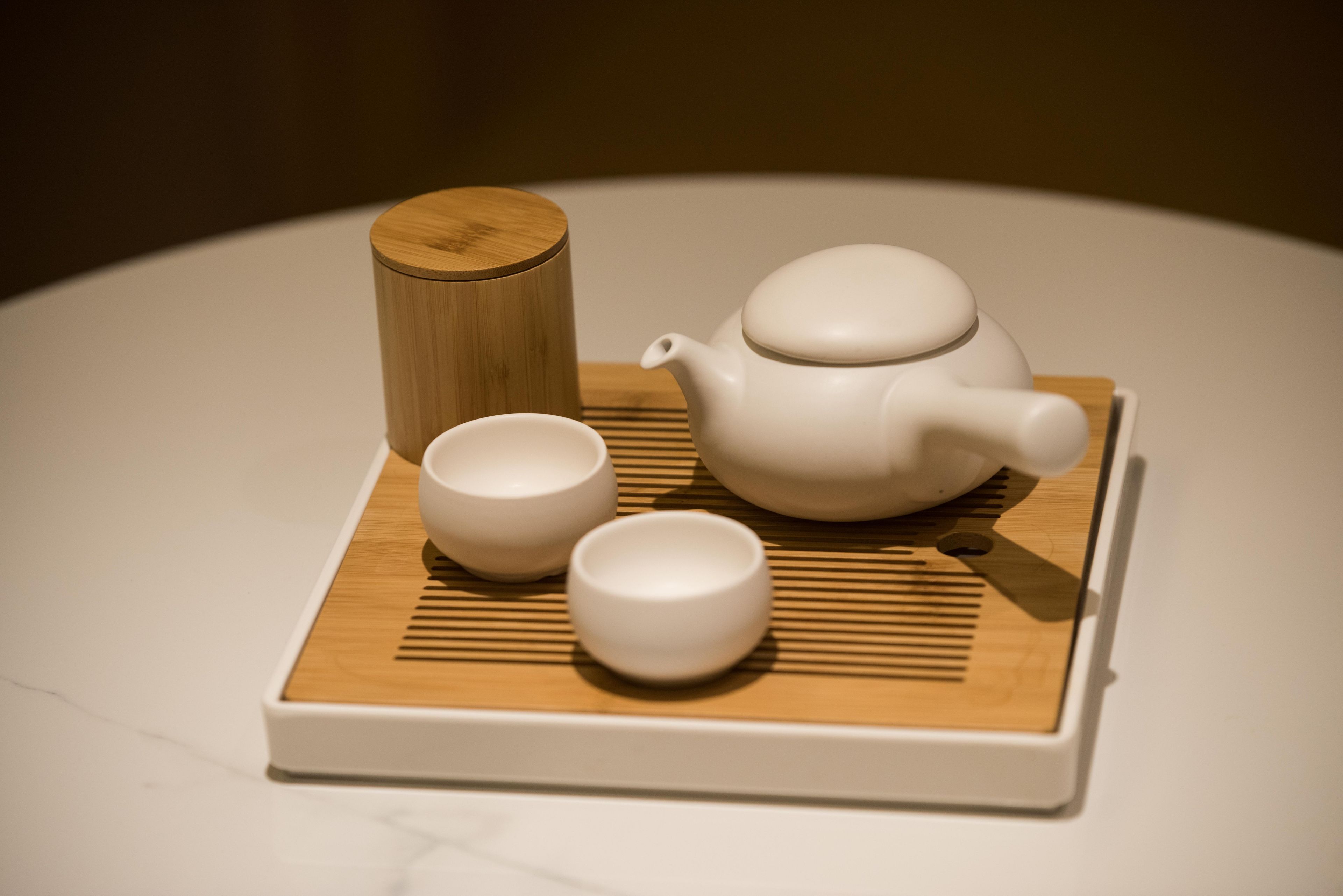 Une théière, deux tasses et un plateau en bois sur une table.