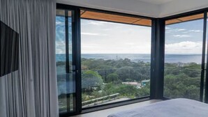 Une chambre dotée d’un grand lit, de portes-fenêtres coulissantes et offrant une vue sur un paysage.