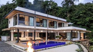 Une maison moderne à deux étages dotée d’une grande piscine extérieure, d’un foyer et d’un jardin bien entretenu.
