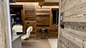 A modern interior with wooden panel walls, a white fluffy chair, a small round table, and a white rug. - Standing megeve - 2 to 8 people - Mont Arbois - ⛷️ and 🏌️‍♀️ (Megeve)
