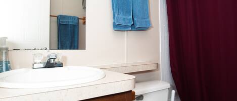 Une salle de bain avec un lavabo blanc, des toilettes et un miroir.