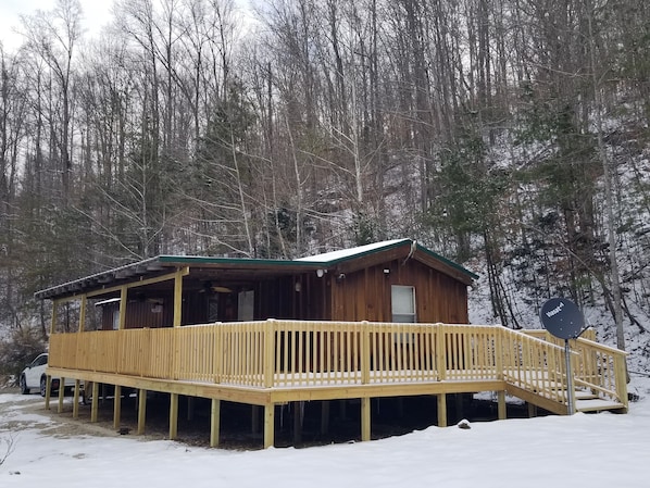 Une cabane en bois avec une terrasse et une antenne parabolique.