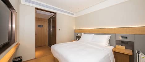 A hotel room with a bed, bedside table, and a television.
