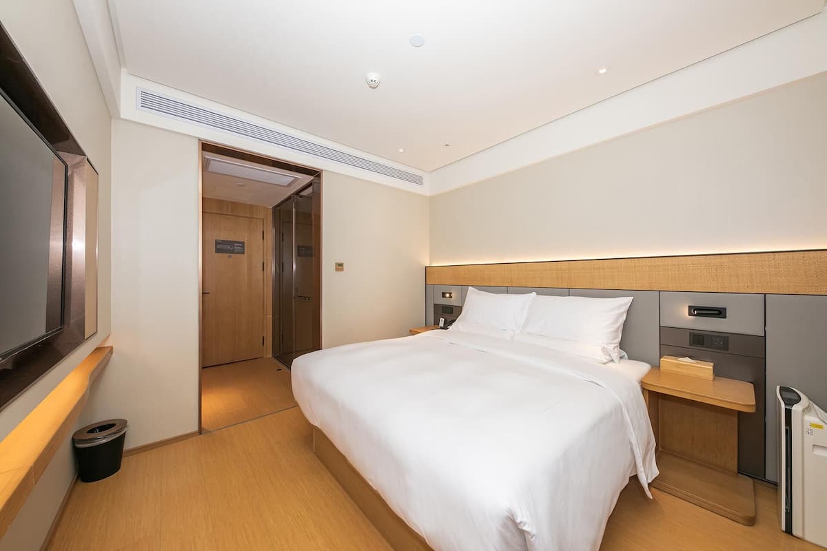 Ein Hotelzimmer mit einem großen Bett, einem Nachttisch, einem Fernseher und einer Badezimmertür.