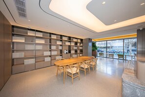 Una biblioteca moderna con una larga mesa de madera y sillas, rodeada de estanterías.
