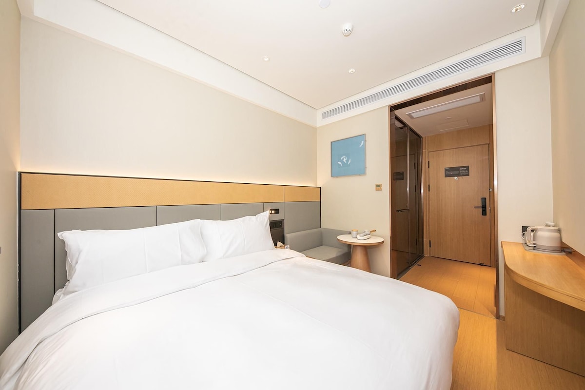 Habitación de hotel con cama, mesita de noche y una pequeña mesa redonda con una taza y platillo.
