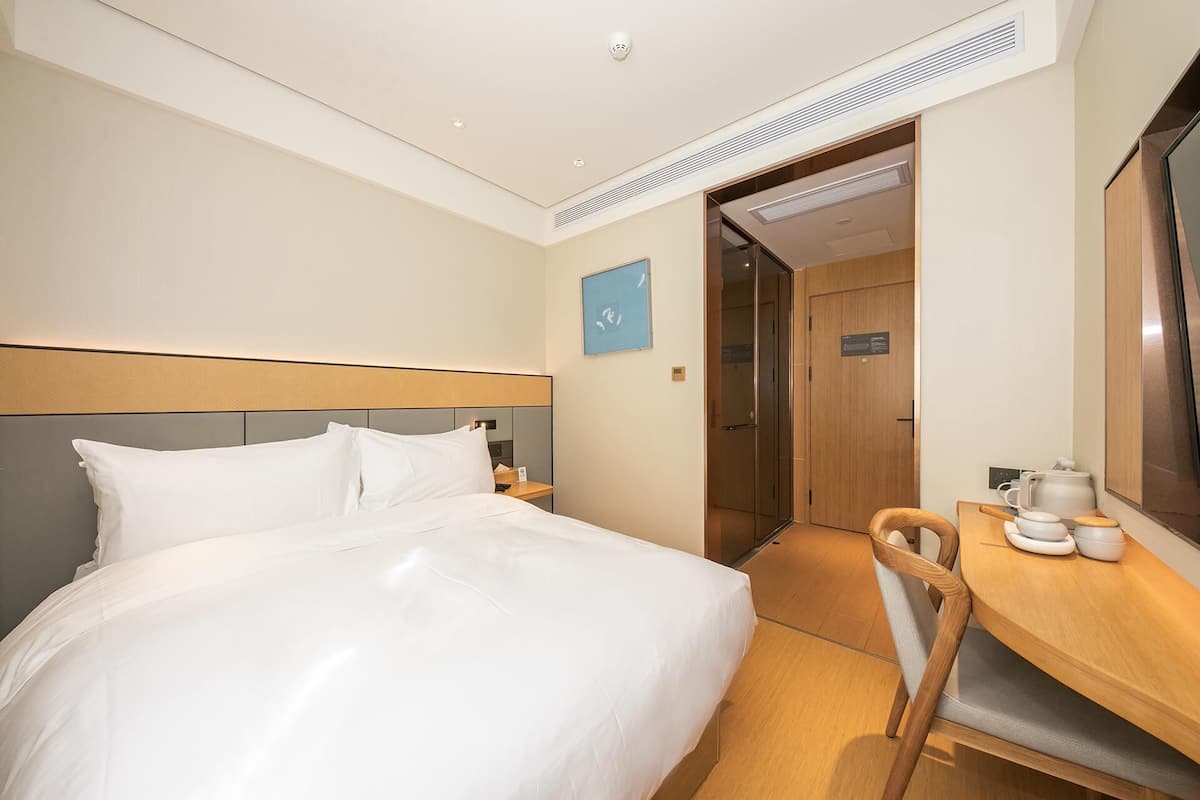 Ein Hotelzimmer mit Bett, Schreibtisch mit Stuhl, Kaffeemaschine und Spiegel.