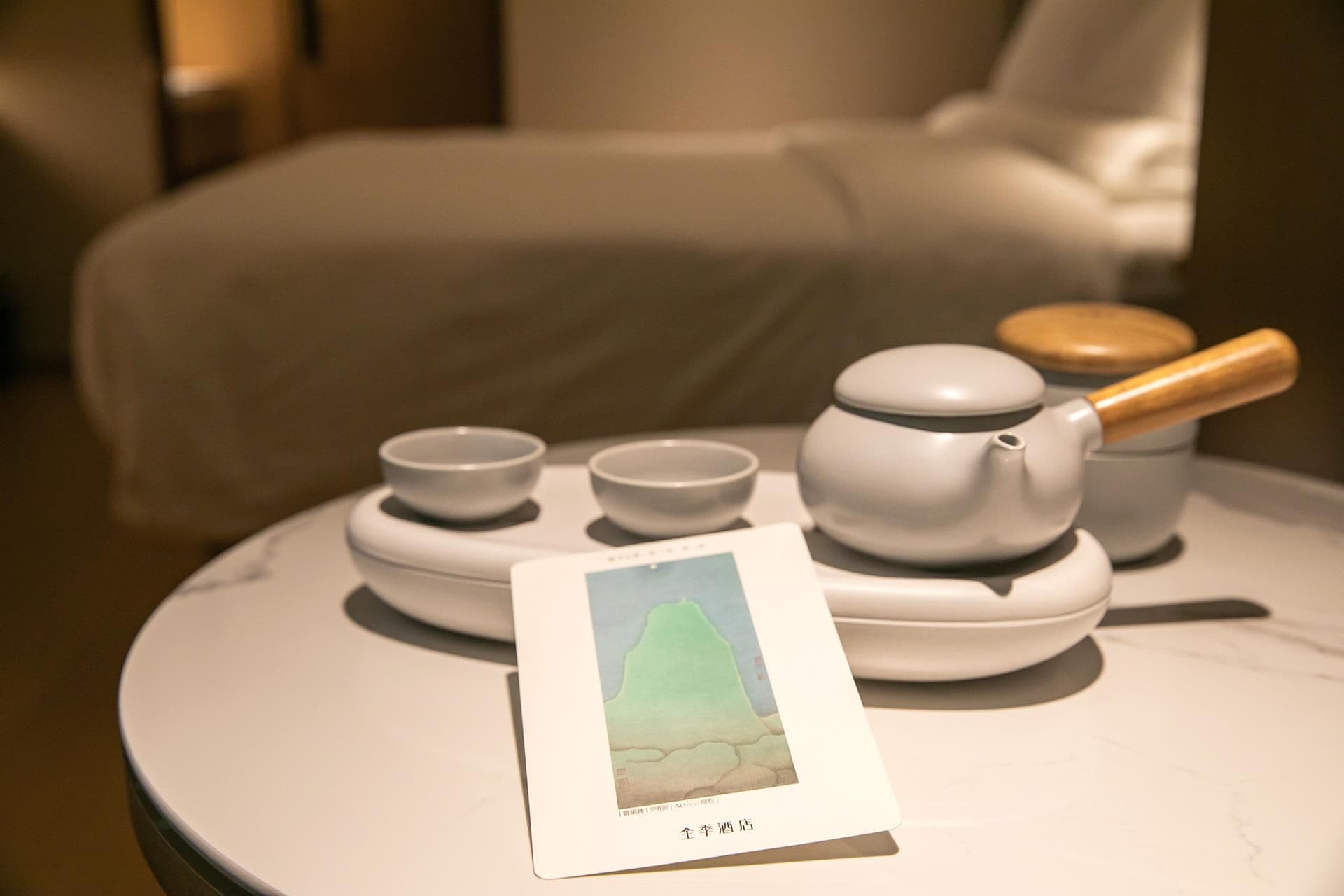 Un service à thé est posé sur une table, à côté d’un tableau encadré.
