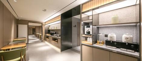 Una hall d'hotel moderna con un'area salotto, angolo cottura e postazione caffè.