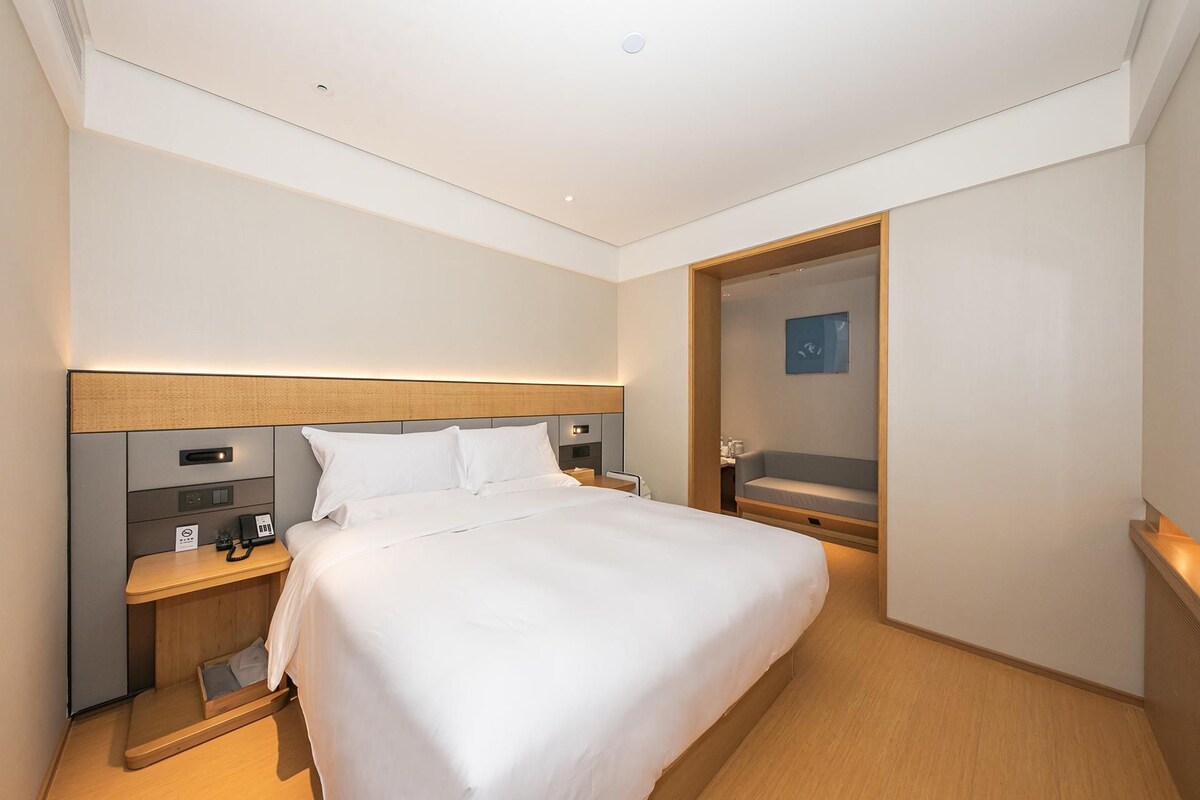 Una habitación de hotel con cama, mesita de noche y una pequeña zona de estar.