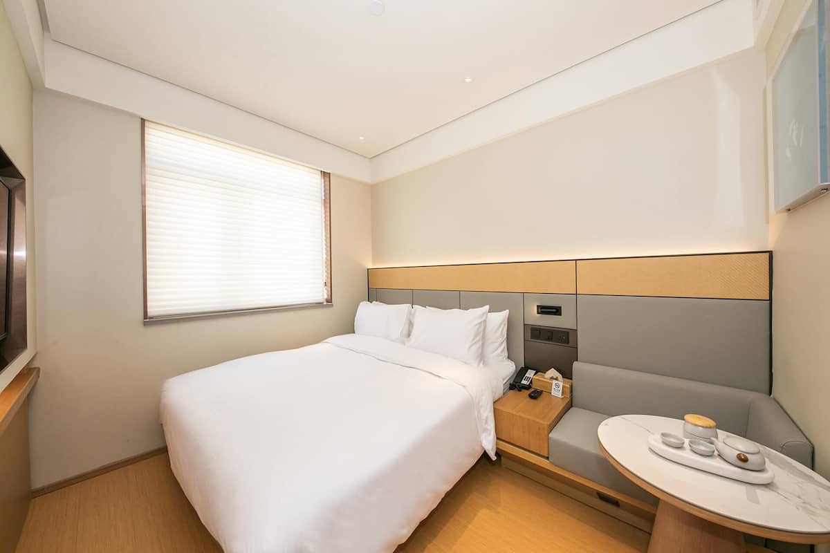 Ein Hotelzimmer mit Bett, Nachttisch und kleinem runden Tisch mit Tablett.