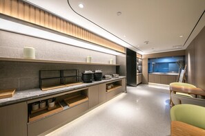 A modern kitchen with a central island, built-in appliances, and a view into the dining area. - Ji Hotel Beijing Sanlitun Taikoo Li (Beijing)