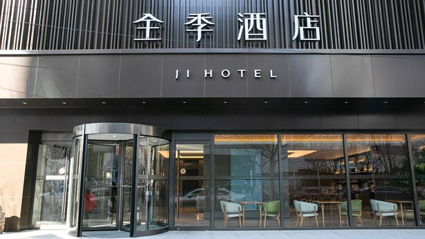 The exterior of Ji Hotel with a modern design, featuring a glass entrance and visible seating area inside.