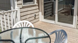 A covered patio area with a glass table and chairs, a sliding glass door, and a window. - Arnolds Park Cabin with kayaks, bikes, and golf cart (Arnolds Park)