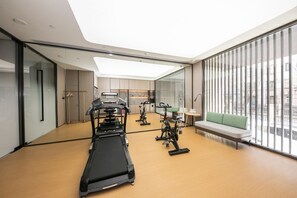 A modern gym with a treadmill, stationary bikes, and a bench. - Ji Hotel (Beijing)